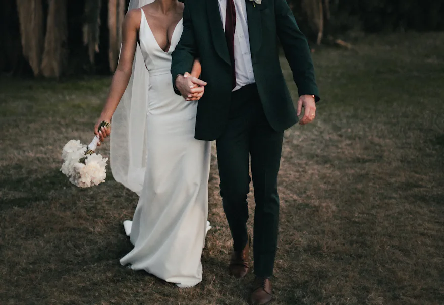 Pareja de recién casados paseando entre árboles al atardecer