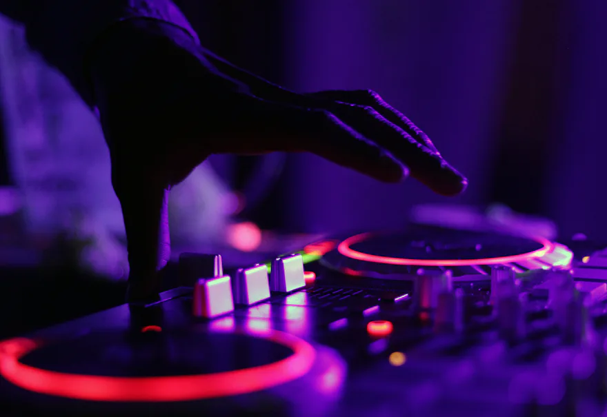Manos de un DJ sobre una mesa de mezclas iluminada